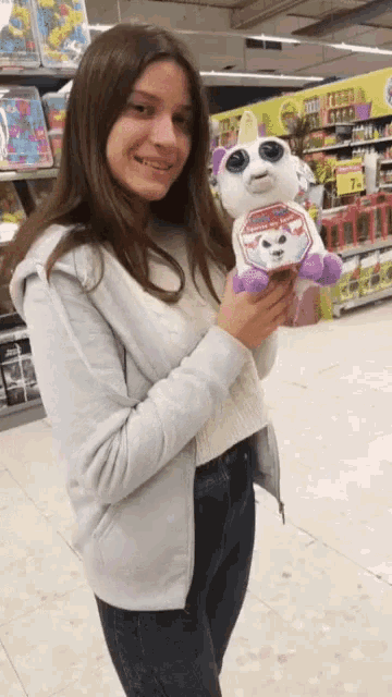 a girl is holding a stuffed unicorn in a store with a price tag that says 7.99