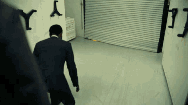 a man in a suit is walking in a dark room with letters y and y on the wall