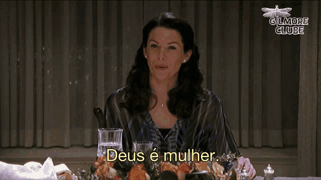 a woman is sitting at a table with flowers and the words deus e mulher in front of her