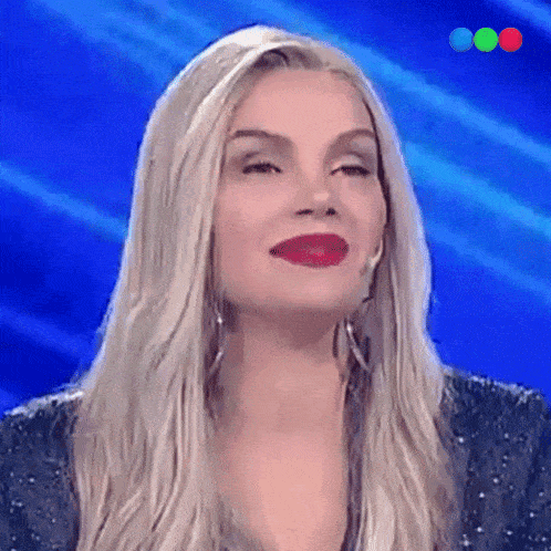 a woman with blonde hair and red lipstick looks at the camera