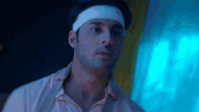 a man with a bandage on his head is standing in front of a blue light .