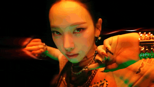 a close up of a woman 's face in a dark room with a green light behind her