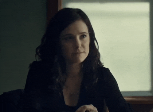 a woman sitting in front of a window with a necklace around her neck