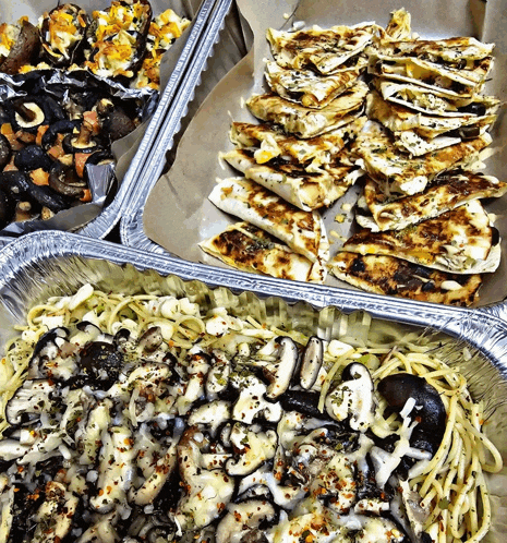 a tray of noodles and a tray of quesadillas sit on a table