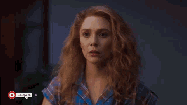 a woman with red hair is wearing a plaid shirt with a youtube subscribe button