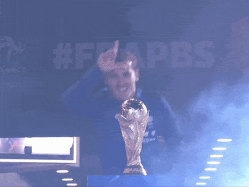 a man is holding a trophy in front of a sign that says #frappbs