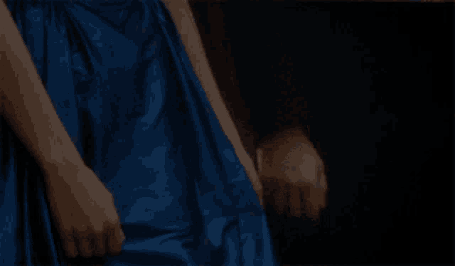 a woman in a blue dress is holding someone 's hand