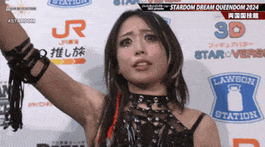 a woman stands in front of a sign that says stardom dream queendom