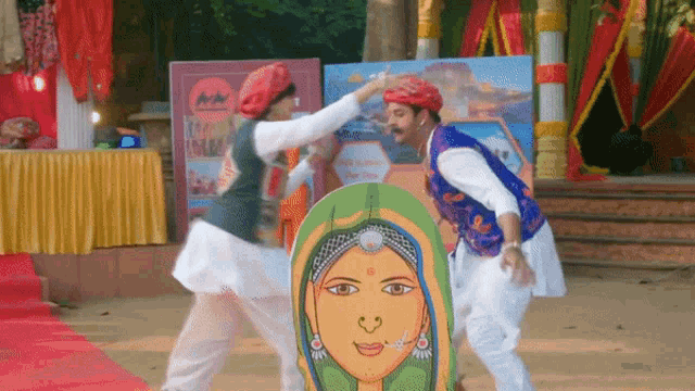 a man and a woman are dancing in front of a sign that says ' rajasthan ' on it