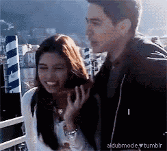 a man and a woman are standing next to each other on a balcony .