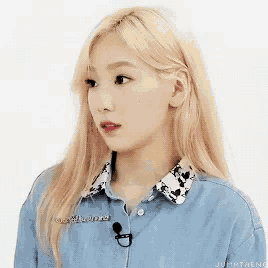 a woman with blonde hair wearing a blue shirt and a microphone .