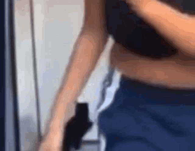 a woman is standing in front of a mirror wearing a black bra and blue shorts .