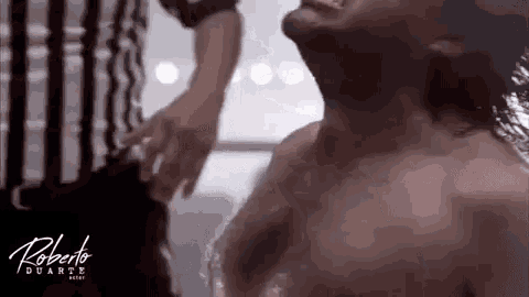 a man without a shirt is being held by a referee in a room .