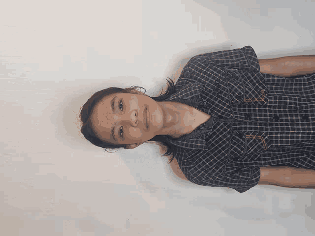 a young man wearing a plaid shirt is laying on his back