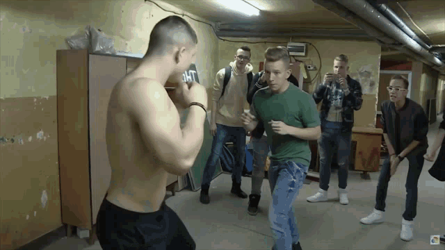 a group of young men are boxing in a room with a sign on the wall that says " 24/7 "