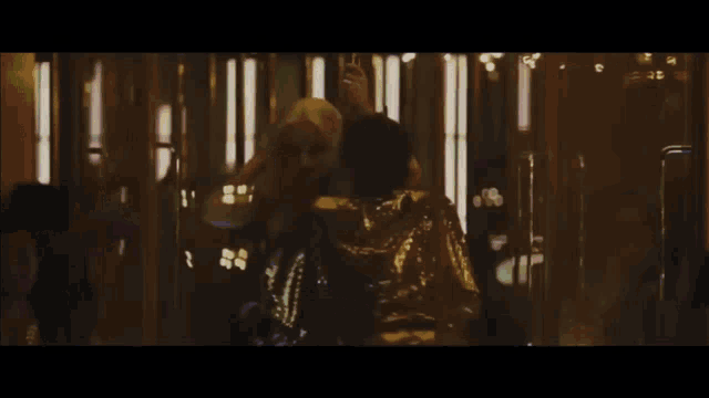 a man and a woman are dancing in a dark room with lights behind them .