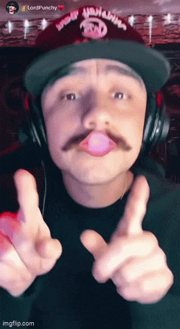 a man wearing headphones and a hat that says lordpunchy blowing a pink bubble