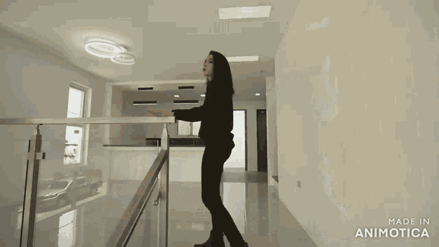 a woman stands in an empty room with the words made in animatica on the bottom right