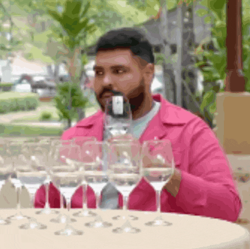 a man in a pink jacket drinks from a wine glass