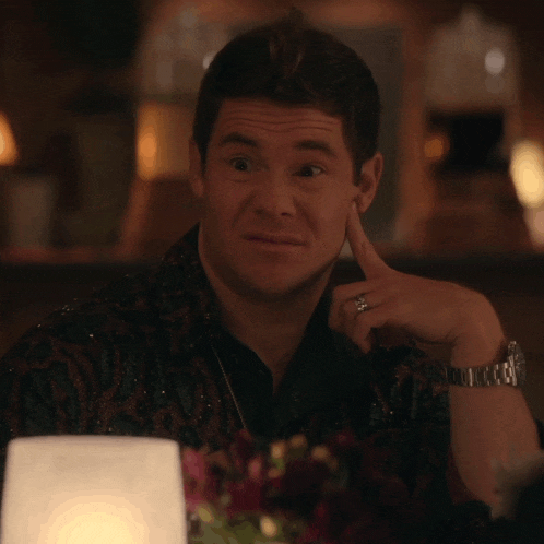 a man sitting at a table with his hand on his chin