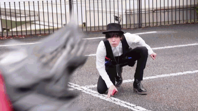 a man in a hat and vest is kneeling down in a parking lot