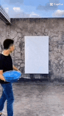 a man is holding a blue frisbee in front of a large white board ..