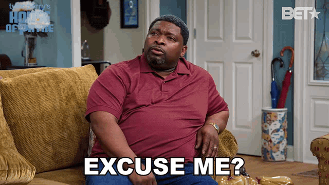 a man sitting on a couch with the words excuse me on his face