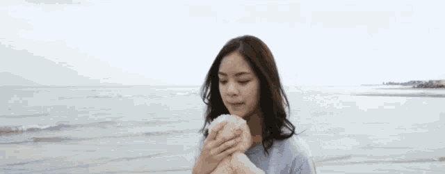 a woman is holding a small dog on the beach