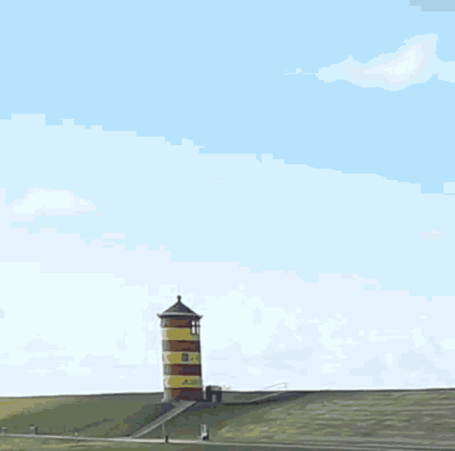 a red and yellow lighthouse on top of a hill