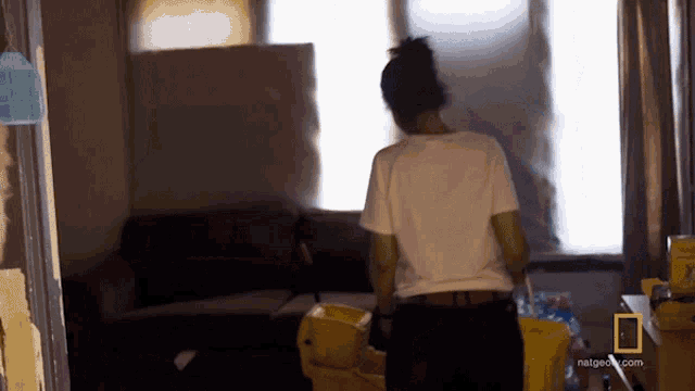 a woman is standing in a living room with a national geographic logo on the corner