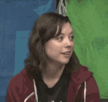 a woman wearing a red hoodie is smiling in front of a blue and green background