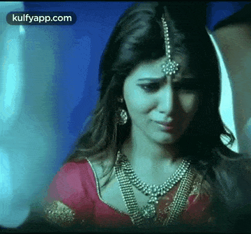 a woman in a red sari is crying and wearing a necklace .