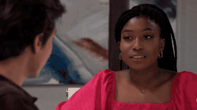 a woman in a pink top looks at a man in a brown shirt