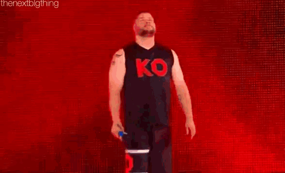 kevin owens is wearing a black tank top with the letter k on it .