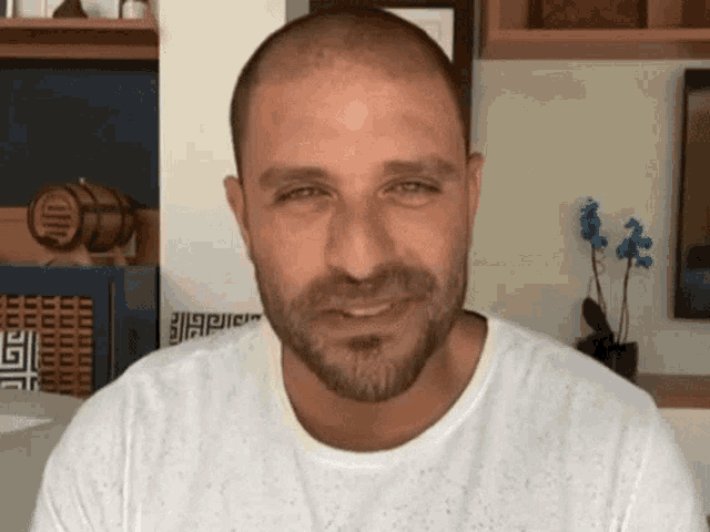 a man with a beard and a white shirt is smiling .