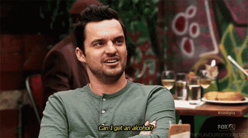a man in a green shirt is sitting at a table talking about alcohol