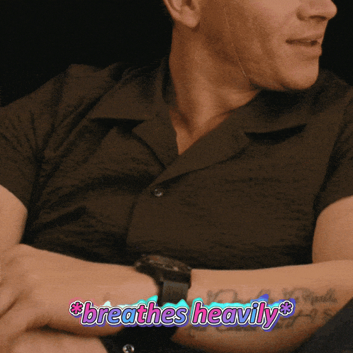 a man wearing a watch and a black shirt with the words breathes heavily on his arm