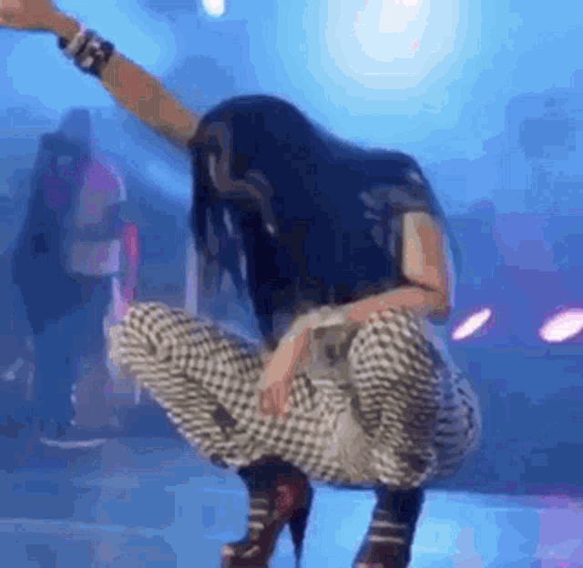 a woman is squatting on a stage with her arms in the air and her legs crossed .