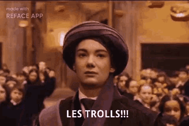 a woman in a hat and tie is standing in front of a crowd of people and says `` les trolls '' .