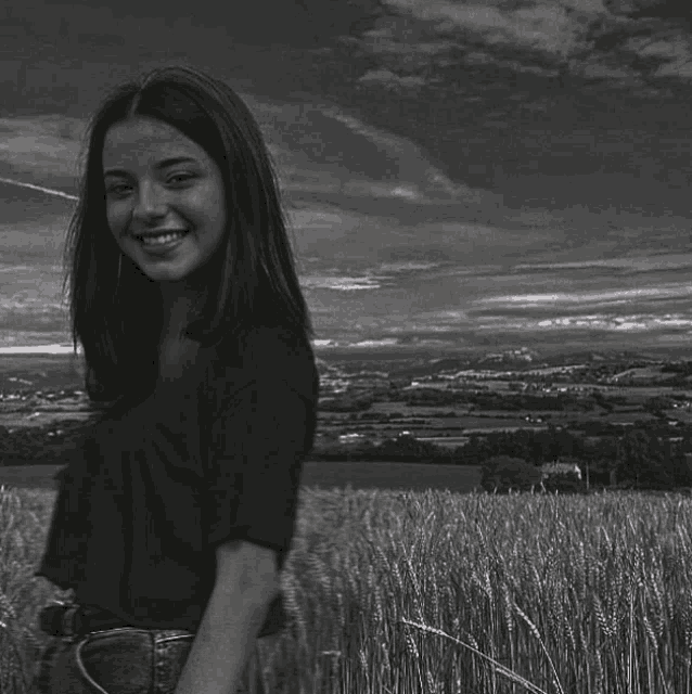 a black and white photo of a girl standing in a field