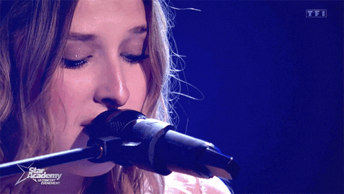 a close up of a woman singing into a microphone with the words star academy in the corner