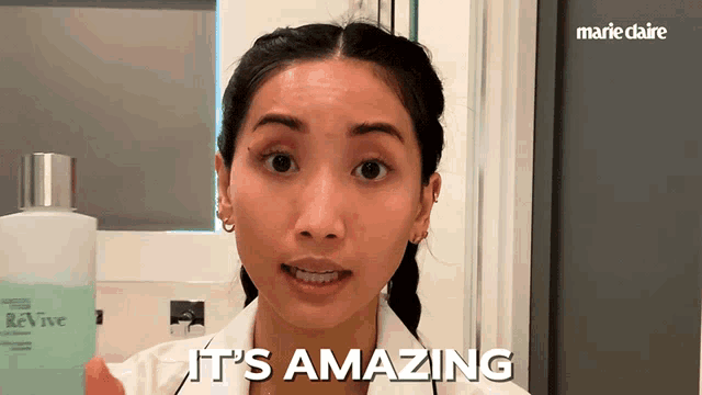a woman holds a bottle of revive lotion and says it 's amazing