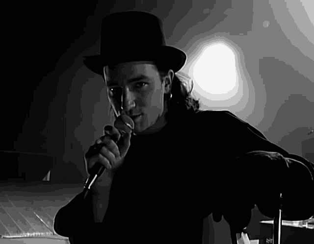 a man in a top hat is singing into a microphone in a black and white photo