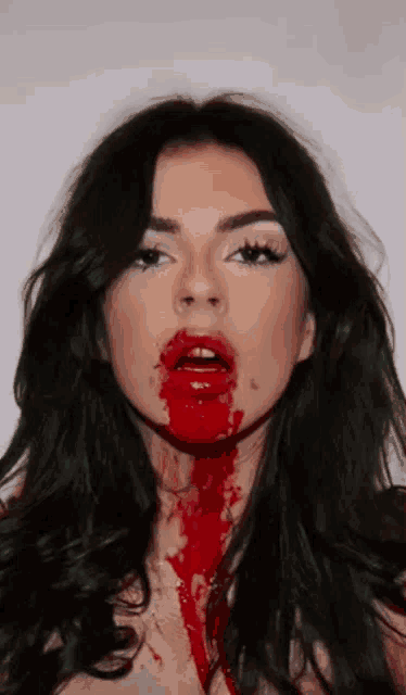 a woman with blood coming out of her mouth looks at the camera