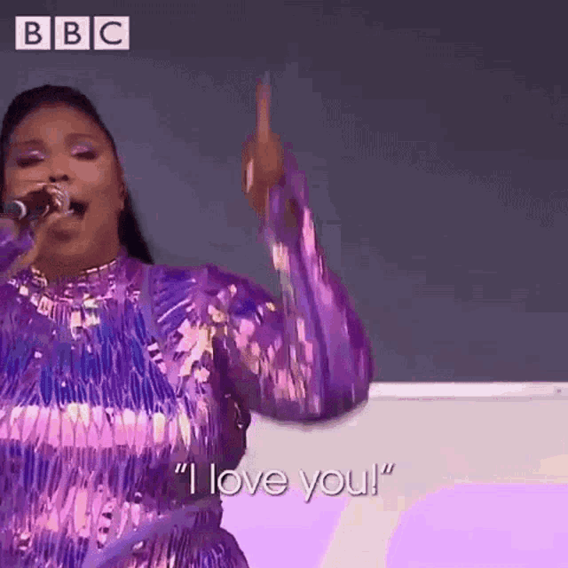 a woman in a purple dress is singing into a microphone and giving a high five .