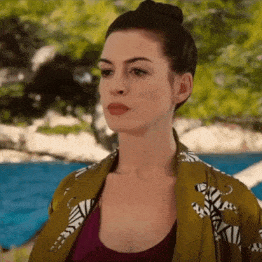 a woman wearing a zebra print jacket and a purple tank top is standing next to a pool .