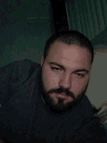 a man with a beard is sleeping with his eyes closed and his hand on his face