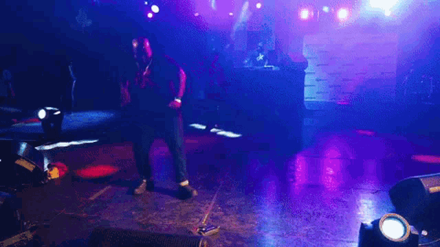a man in a black shirt with the letter k on it stands on a stage