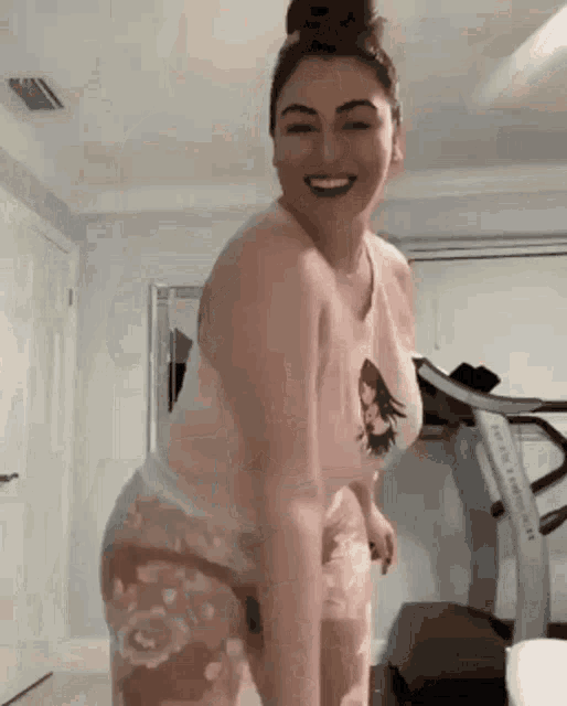 a woman is standing in a room with a treadmill in the background .