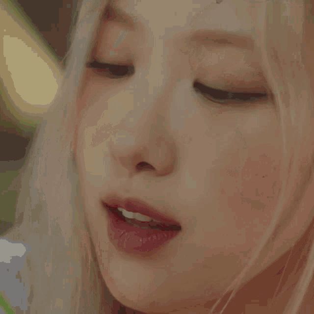 a close up of a woman smelling a red rose in her mouth .
